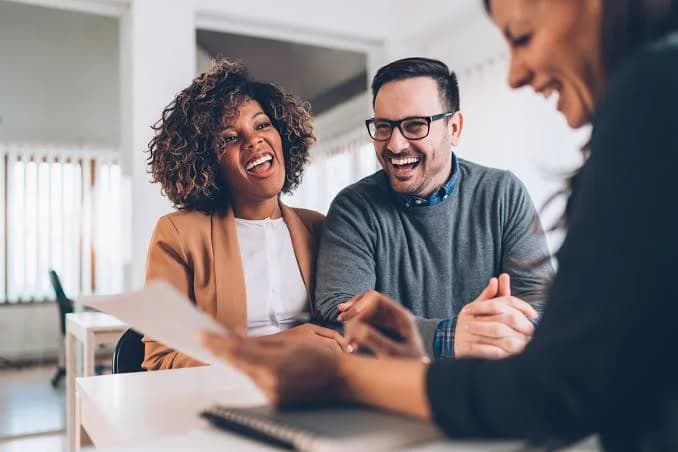 Two smiling clients reviewing a document with a Zenvix team member